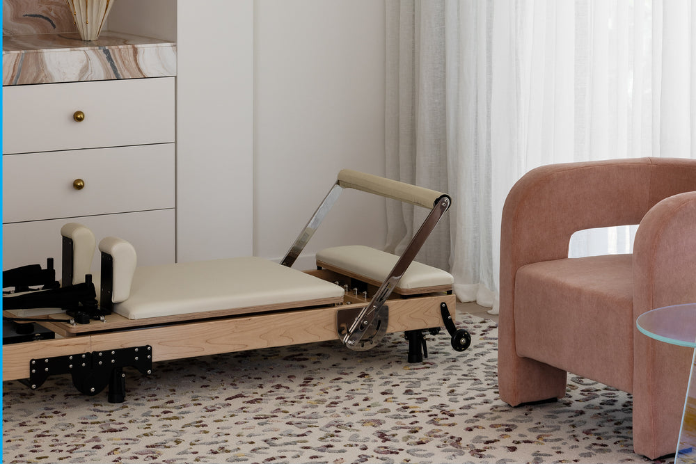 Compact Folding Reformer - Ivory Upholstery with Pink Chair in Bedroom Setting | Your Reformer